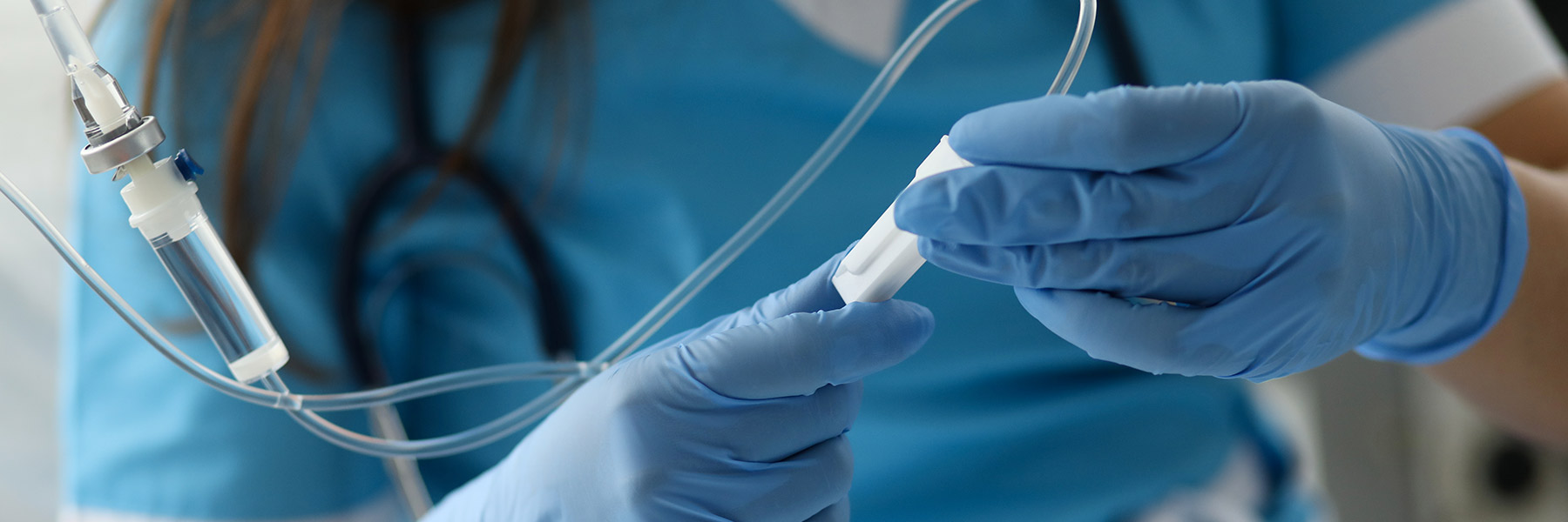A close-up of a nurse’s gloved hands holding an IV
